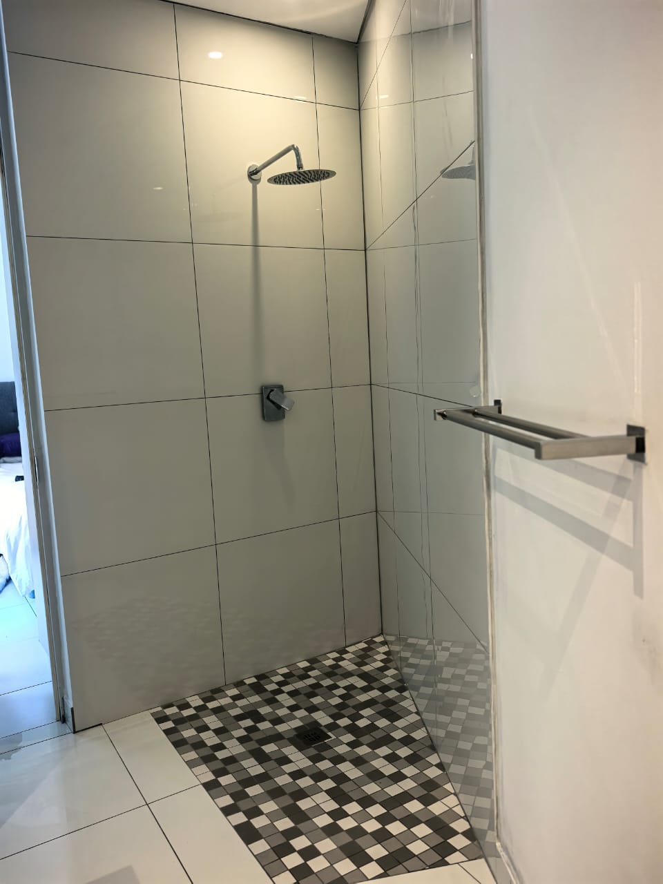 Renovated walk-in shower with large-format tiles and mosaic floor